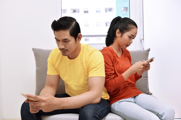 portrait-asian-couple-busy-with-their-mobile-phones-their-hand_9083-1131.jpg